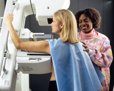 微笑的女人站在另一个女人旁边乳房X光机